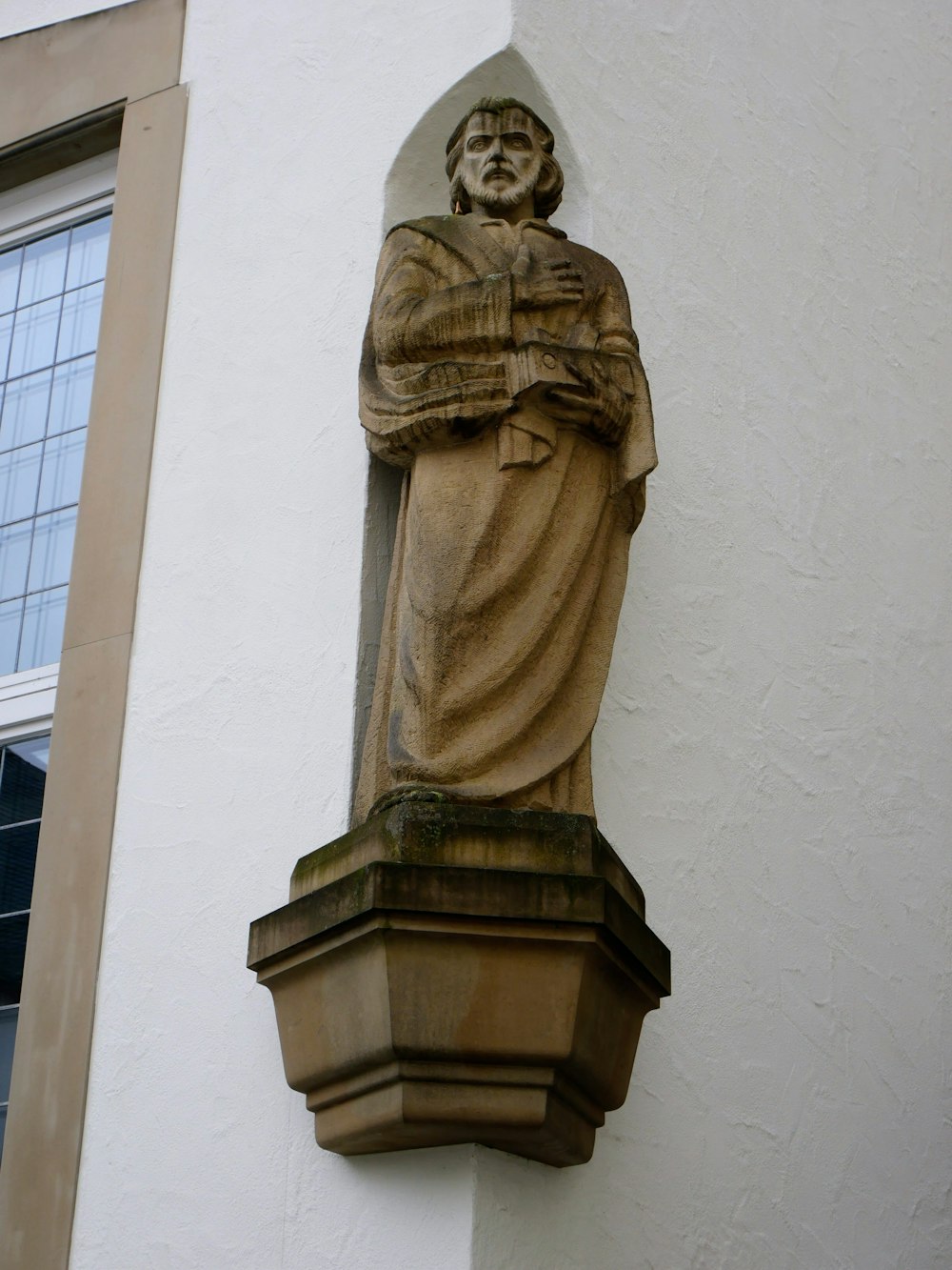 a statue of a man holding a book on the side of a building