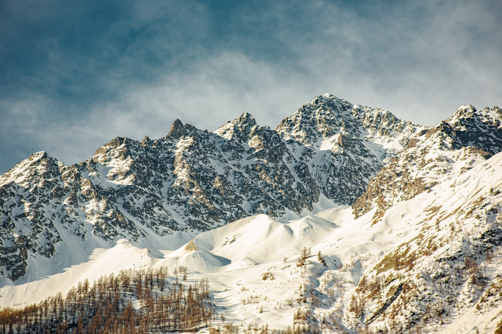 a mountain covered in snow under a cloudy sky