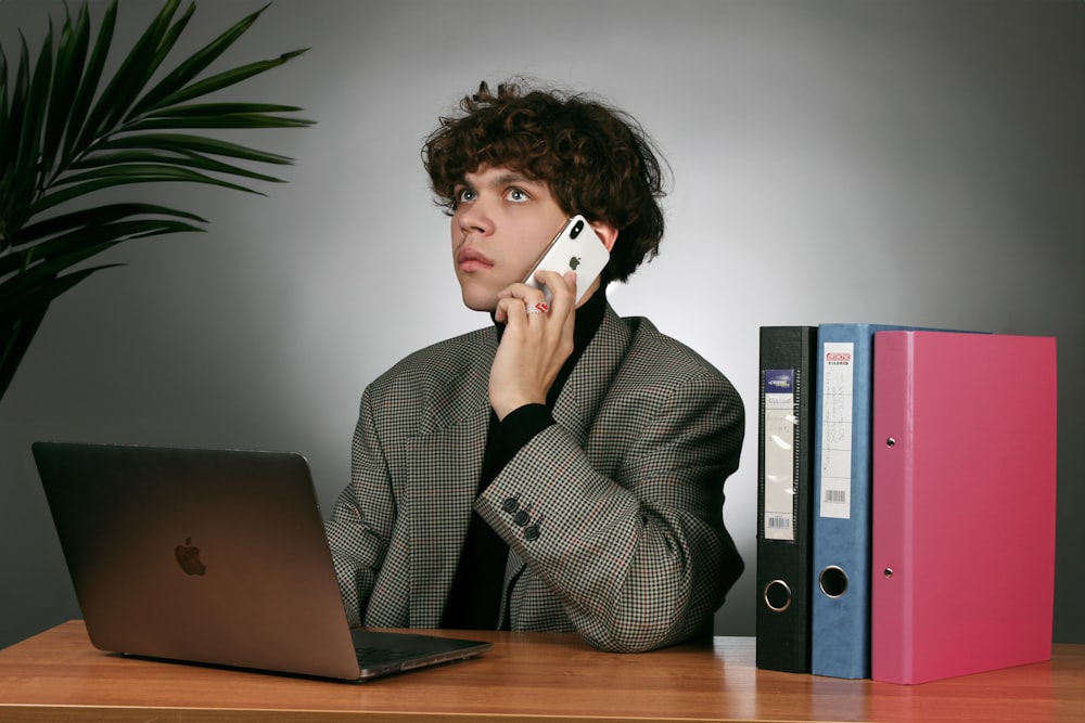 a man sitting at a desk talking on a cell phone