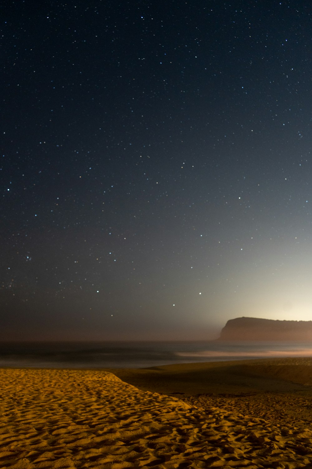 a night sky with stars above a beach