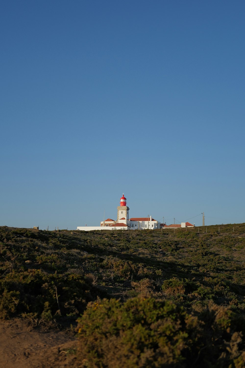 a lighthouse on top of a hill with a sky background