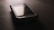 A vintage smartphone is lying on a dark surface, with a slightly reflective screen and a visible brand name above the display. The phone's surface has scuff marks, indicating wear and tear.