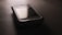 A vintage smartphone is lying on a dark surface, with a slightly reflective screen and a visible brand name above the display. The phone's surface has scuff marks, indicating wear and tear.