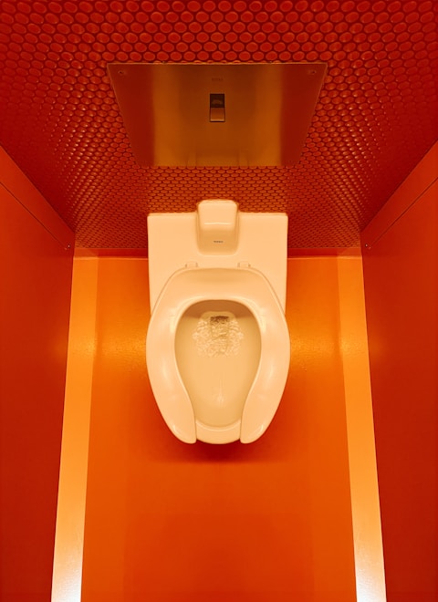 a white toilet sitting in a bathroom next to a red wall