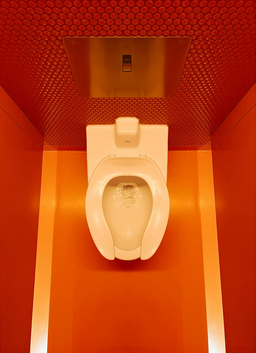 eine weiße Toilette in einem Badezimmer neben einer roten Wand