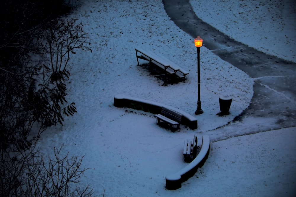 a park bench covered in snow next to a street light