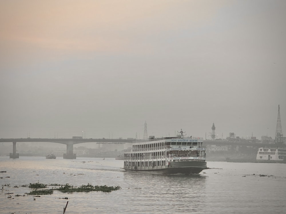 a large boat floating on top of a river next to a bridge