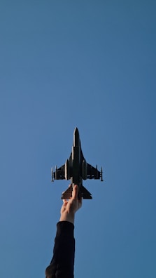 Hand holding a small, intricate airplane model against a sky background.