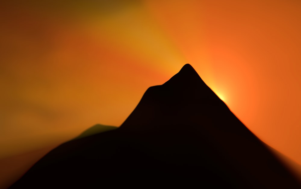 a silhouette of a mountain with the sun in the background