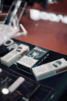 Several boxes of vaping products are displayed on a countertop. The boxes contain warnings about nicotine being a highly addictive substance. The setting appears to be a retail environment, possibly a vape shop.