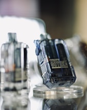 A close-up view of transparent electronic devices with a modern, sleek design placed on a mirrored surface. The focus is on a device labeled 'aspire GOTEK.' Other similar devices are blurred in the background, creating a futuristic and technological atmosphere.