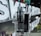 A transparent vaping device with the brand name 'aspire GOTEK X' is displayed prominently in front of illuminated letters spelling 'SK E-CRYSTAL'. The device is placed on a reflective surface, and the background includes various product boxes with colorful packaging.