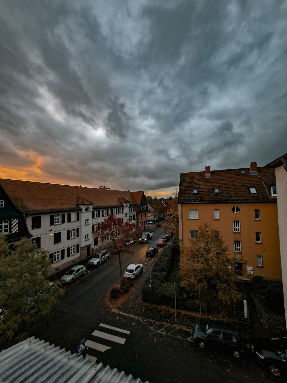 a cloudy sky over a city street with parked cars