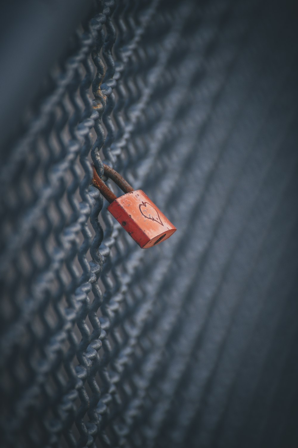 a red padlock on a chain link fence