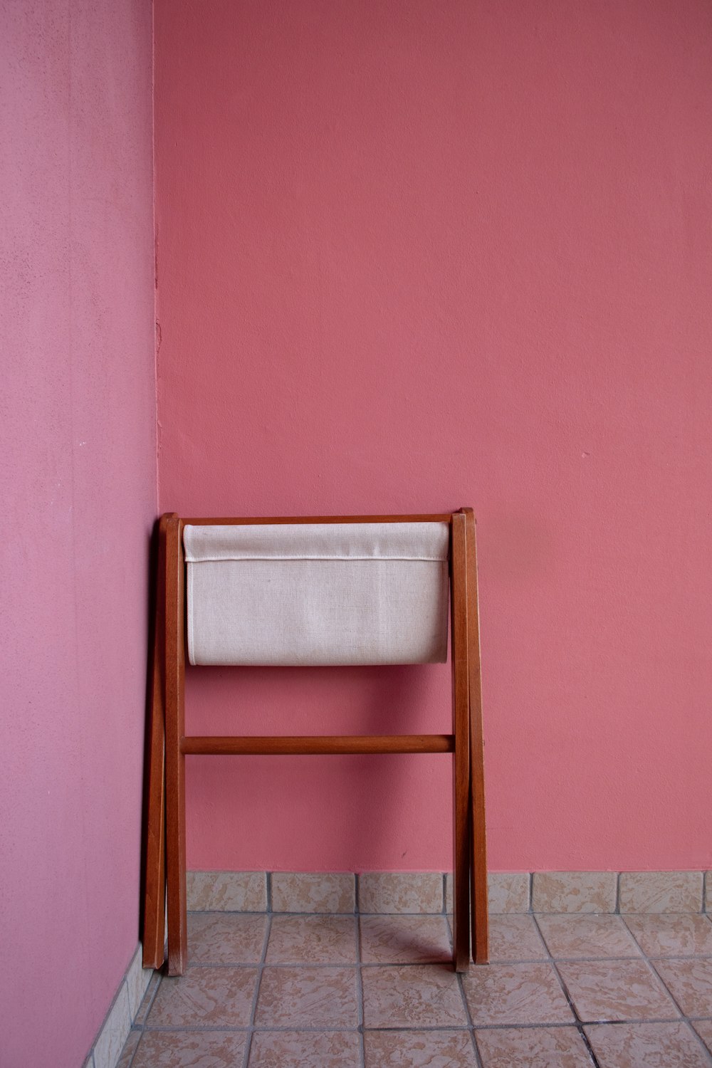 a wooden chair against a pink wall in a room