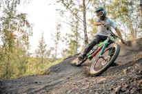 An action shot of a person wearing Fortiva protective gear while biking through a forest trail.
