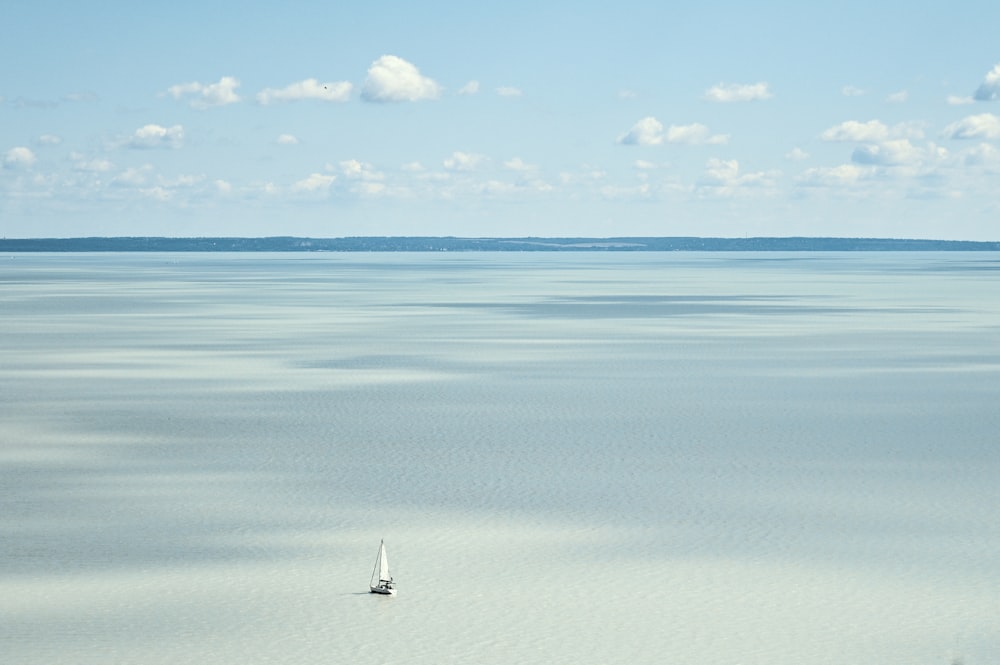 a lone sailboat in the middle of a large body of water