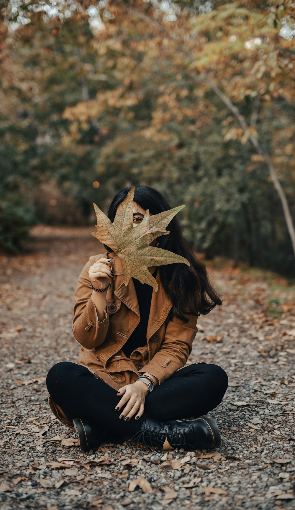 a woman sitting on the ground with a leaf in her mouth