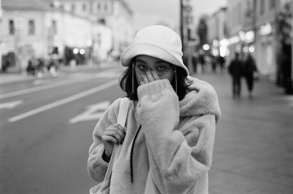 a woman covers her face while walking down the street