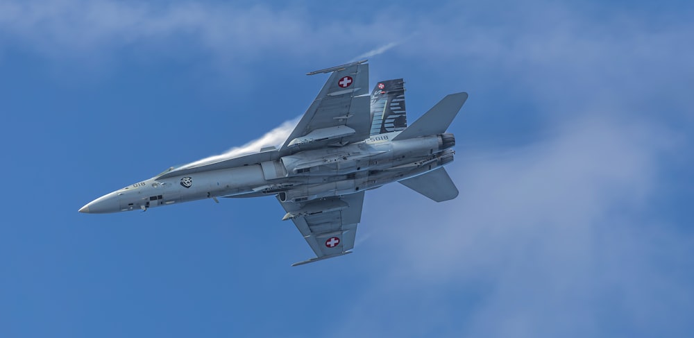 a fighter jet flying through a blue sky