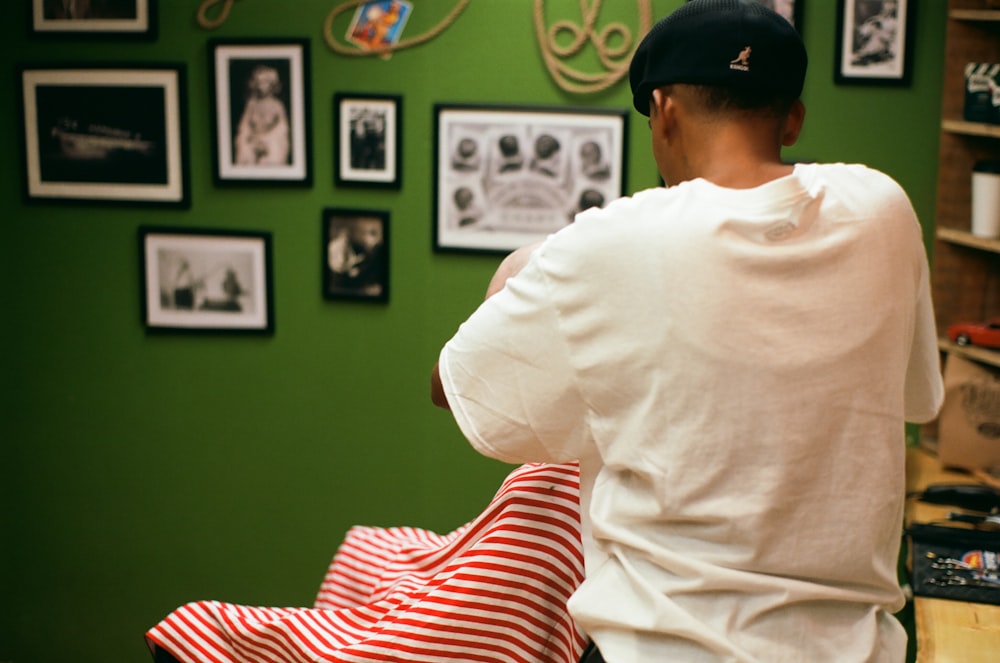 a man sitting in front of a green wall