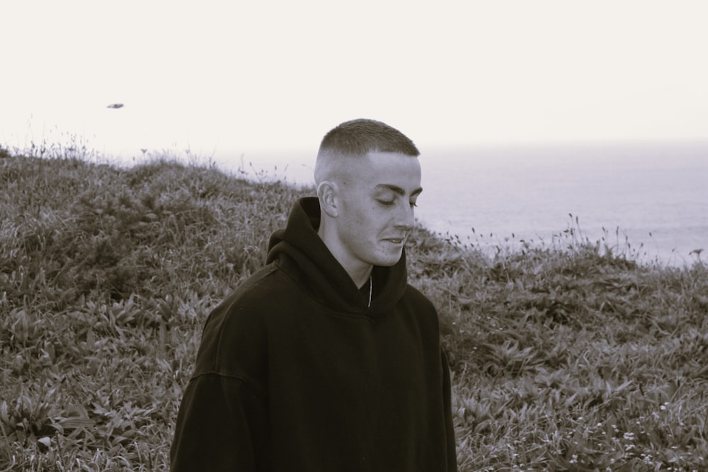 a man in a black hoodie standing in a field