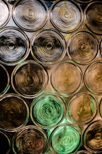 An array of circular patterns composed of concentric rings, with a reflective and slightly transparent appearance. The circles are arranged in a grid, and there are varying shades of brown, yellow, and green, giving the image a textured look.