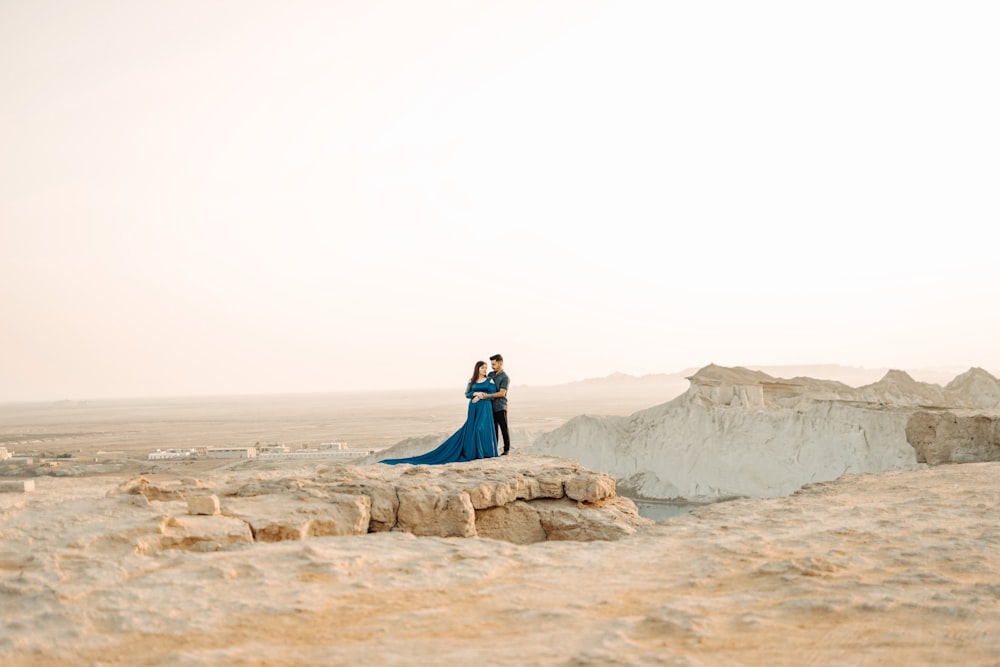 a man and woman standing on top of a mountain