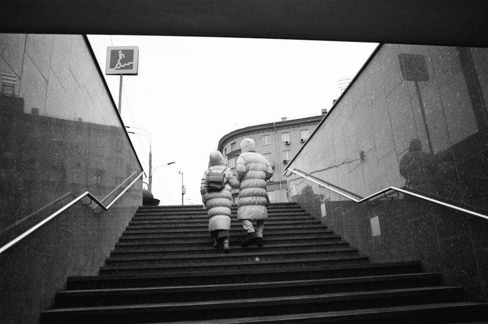 eine Person in einem bauschigen Mantel, die eine Treppe hinaufsteigt