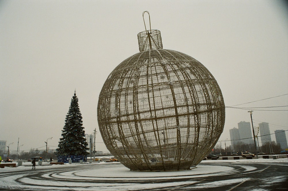 una gran escultura de bola de metal en medio de un parque