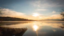 Golden sunrise over a serene mountain lake reflecting vibrant colors.