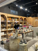 A lively pop-up booth with lumiflamme candles displayed on rustic wooden shelves, customers browsing happily.