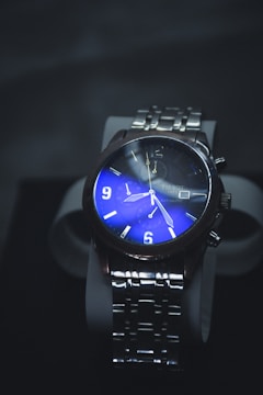A luxurious wristwatch with a stainless steel strap and a striking blue dial. The watch face features illuminated numbers and hands, with additional dials for extra functionality.