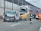 A collision involving a large truck, a van with significant front-end damage, and a street sweeper on a highway. Emergency responders, including firefighters and a person in orange, are present at the scene. The road is partially blocked, and debris is scattered across the pavement.