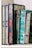 A row of intricately designed, colorful books with ornate calligraphy and decorative patterns. The books are primarily in shades of blue, green, and red, and are arranged neatly on a shelf.