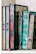 A row of intricately designed, colorful books with ornate calligraphy and decorative patterns. The books are primarily in shades of blue, green, and red, and are arranged neatly on a shelf.