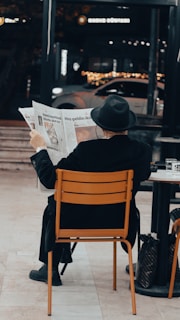 a man sitting at a table reading a newspaper