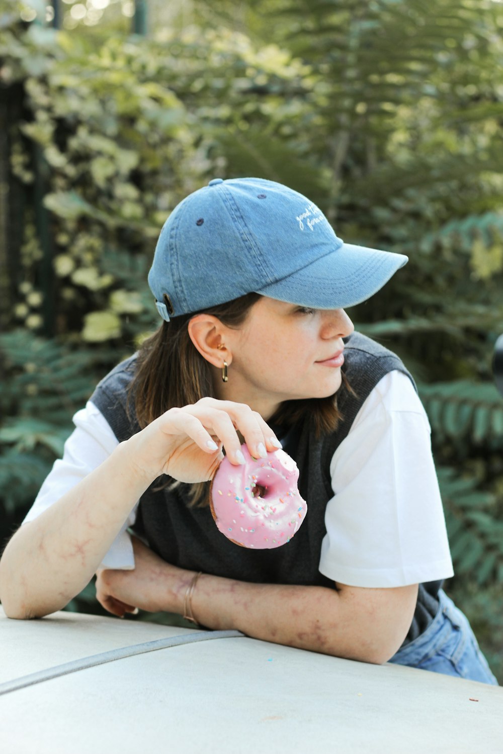 a woman sitting at a table with a doughnut in her hand