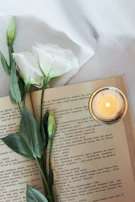 A candle casting a soft glow over an open Bible and a cup of tea.
