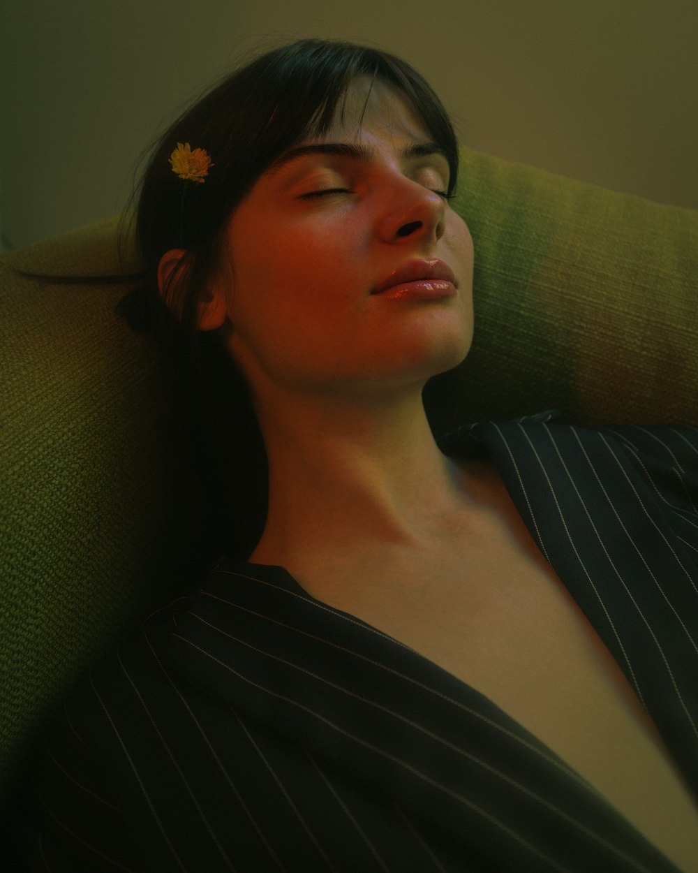 a woman sleeping on a couch with a flower in her hair
