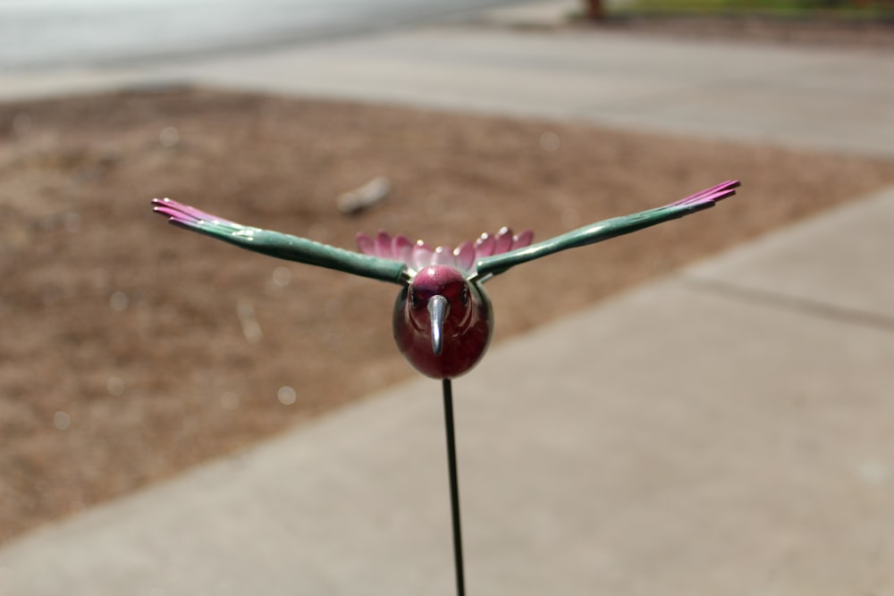 a pink flower with a green bird on top of it