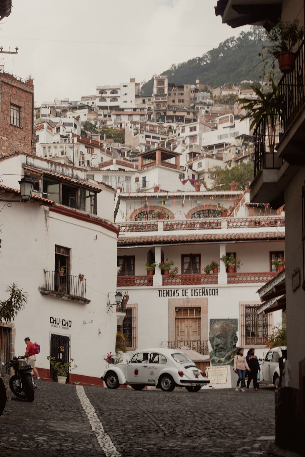 a cobblestone street with cars parked in front of buildings