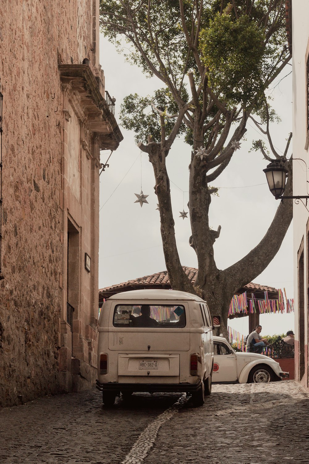 a white van driving down a street next to a tree