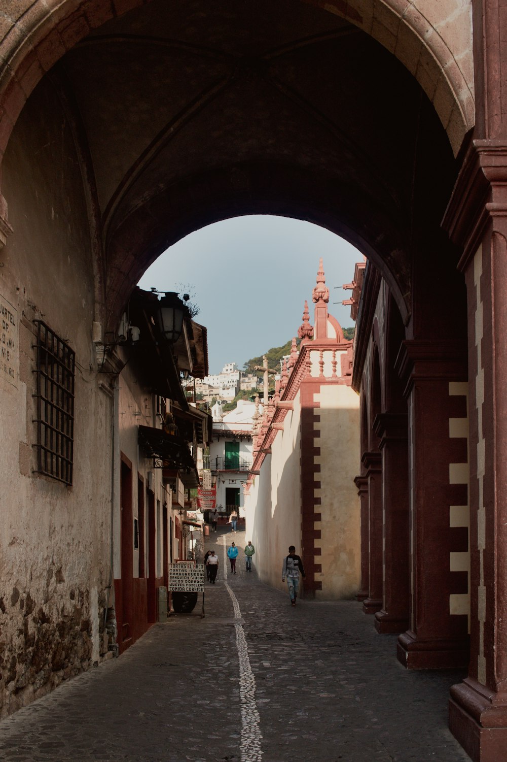 a person walking down a street under an archway