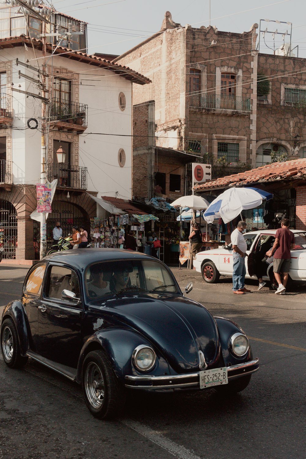 a black car driving down a street next to tall buildings