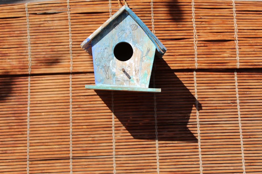 a blue birdhouse hanging on a bamboo wall