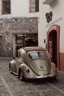 A classic Volkswagen Beetle parked on a sunlit cobblestone street, capturing its timeless charm.