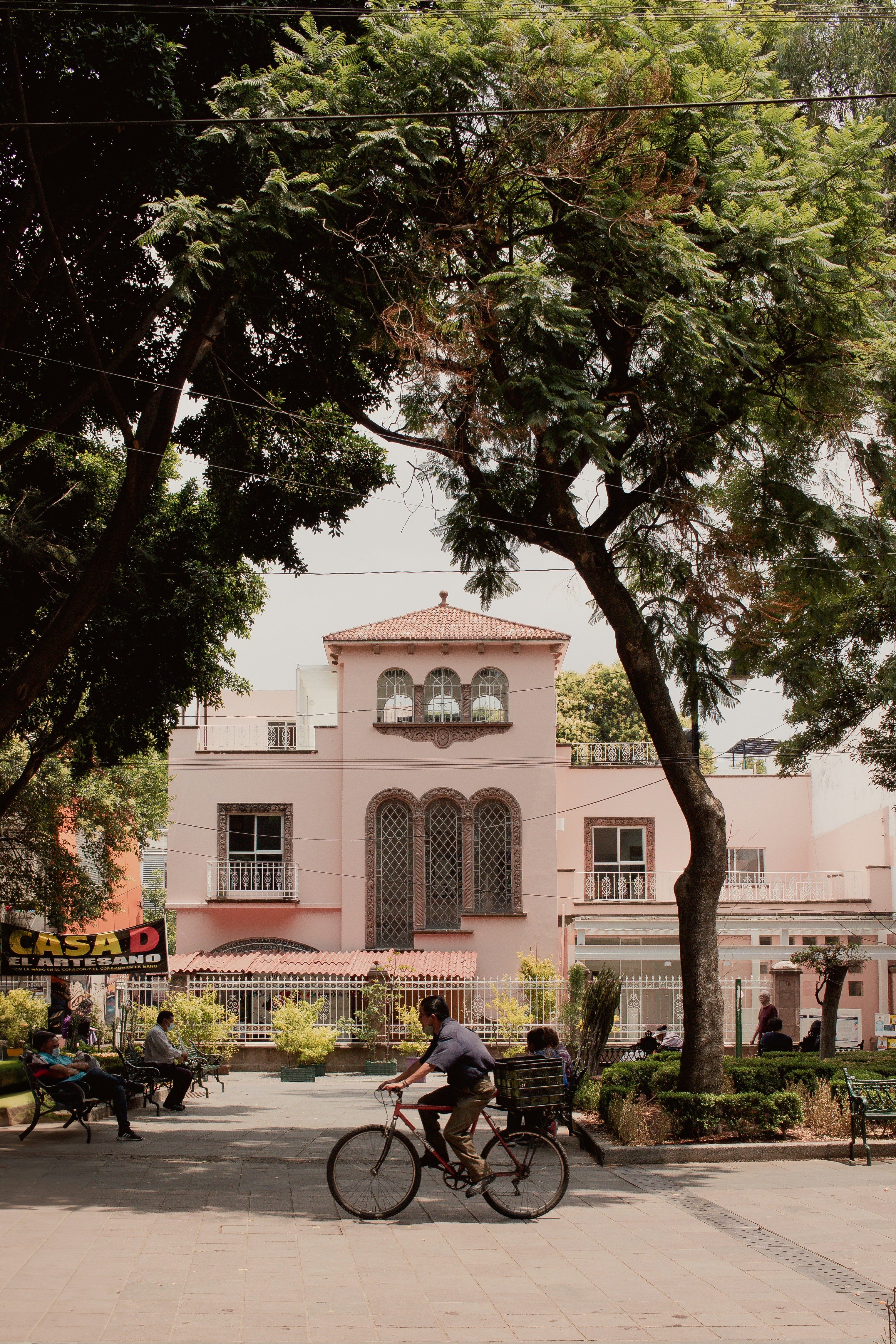 a man riding a bike past a pink building