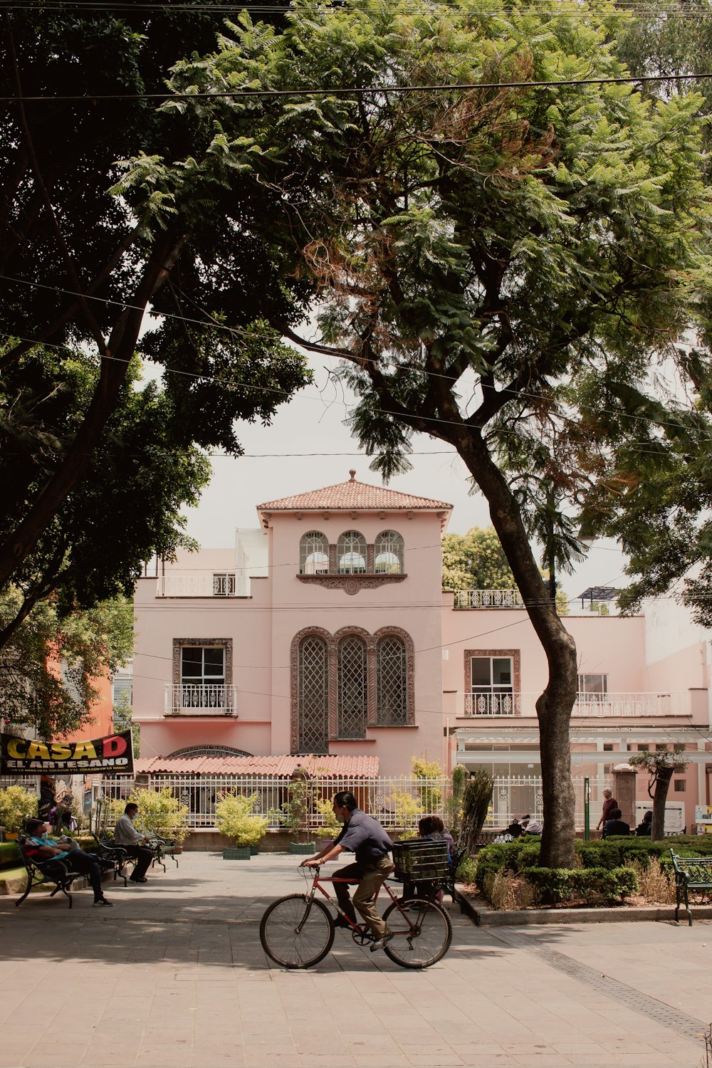 a man riding a bike past a pink building