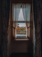 A cozy home with wooden framed sliding windows overlooking a garden in autumn.